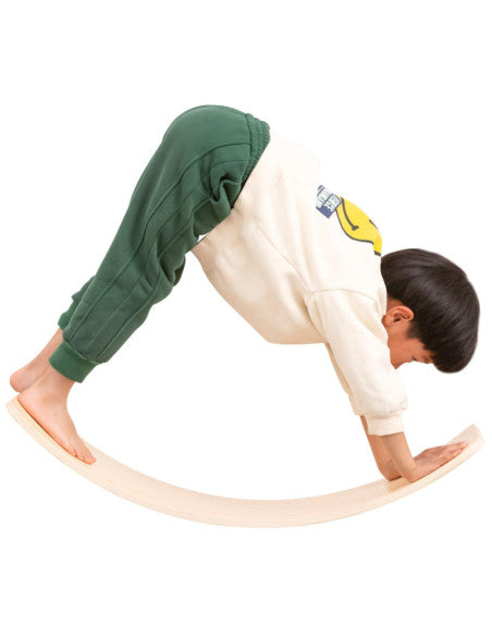 Enfant faisant du yoga sur la planche d'équilibre en bois