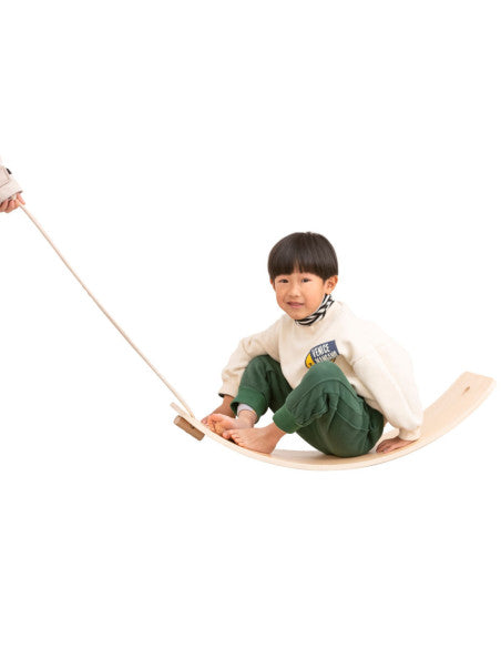 Enfant assis sur la planche d'équilibre Viga avec corde